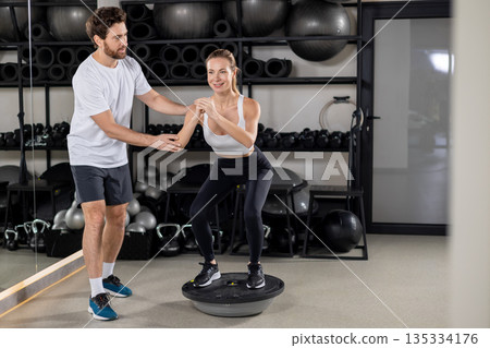Blonde young woman exercising in the gym with a coach 135334176