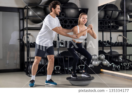 Blonde young woman exercising in the gym with a coach 135334177