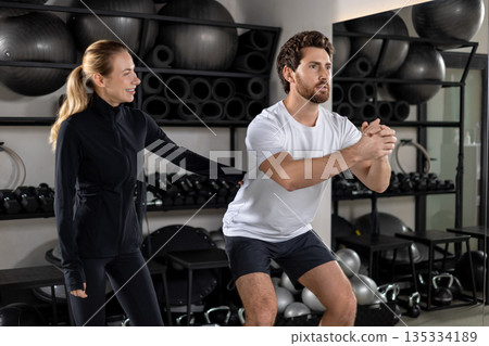 Blonde young female coach training a young man during interval workout Blonde young female coach training a young man during interval workout 135334189