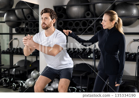 Blonde young female coach training a young man during interval workout Blonde young female coach training a young man during interval workout 135334190