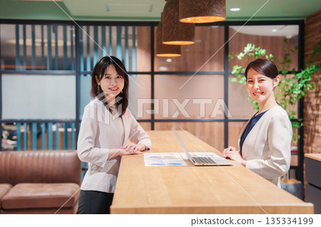 Two working women smiling at the camera Two working women smiling at the camera 135334199
