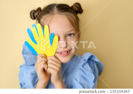 The child shows yellow and blue hand prints cut out of cardboard, symbolizing down syndrome. 135334367