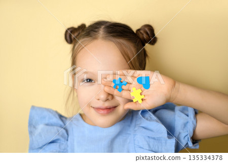 A girl in a blue dress shows the symbol of down syndrome on the palm of her hand. Support and mercy for children with special needs 135334378