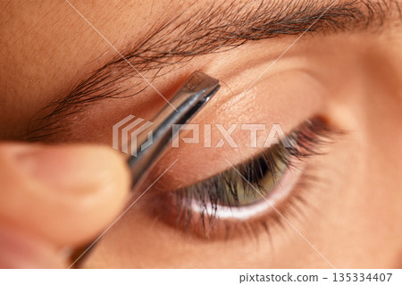 Woman tweezing her eyebrow, shaping and maintaining facial appearance 135334407