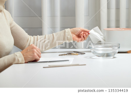 Woman's hand pulling a white tissue from a dispenser for hand hygiene Woman's hand pulling a white tissue from a dispenser for hand hygiene 135334419