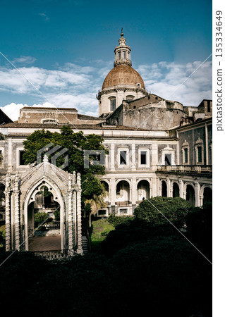 Benedictine Monastery Of San Nicolo Arena In Catania, Sicily: Historic Baroque Courtyard With Arched Walkways, Stone Facades, And Domed Church Structure 135334649