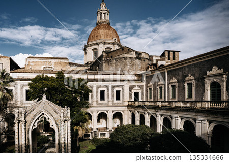 Benedictine Monastery Of San Nicolo Arena In Catania, Sicily: Historic Baroque Courtyard With Arched Walkways, Stone Facades, And Domed Church Structure 135334666