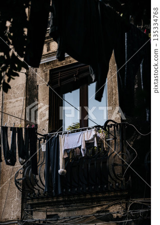 Hanging Laundry In Catania Courtyard With Italian Style: Colorful Clothes Drying On Lines Between Residential Buildings In Quiet Everyday Urban Scene Hanging Laundry In Catania Courtyard With Italian Style: Colorful Clothes Drying On Lines Between Residential Buildings In Quiet Everyday Urban Scene 135334768