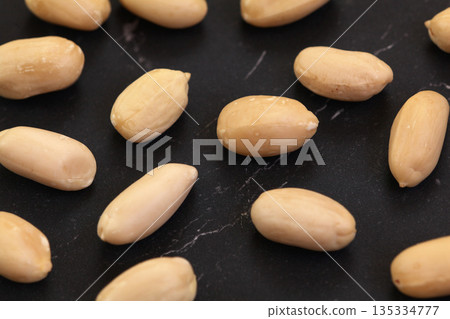 Group of peeled peanuts on black marble like board, closeup detail from above Group of peeled peanuts on black marble like board, closeup detail from above 135334777