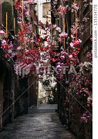 Narrow Alley Decorated With Pink Flowers: Stone Walls And Hanging Floral Arrangements Creating Colorful Mediterranean Urban Passageted With Pink Flowers: Stone Walls And Hanging Floral Arrangements 135334778