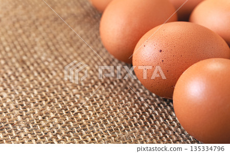 Beige coloured eggs on jute textile cloth, closeup detail, space for text left down corner 135334796