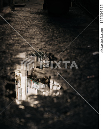 Urban Reflections In Catania Street: Italian City Architecture Mirrored In Rain Puddle Creating Abstract Light And Shadow Composition Urban Reflections In Catania Street: Italian City Architecture Mirrored In Rain Puddle Creating Abstract Light And Shadow Composition 135334815