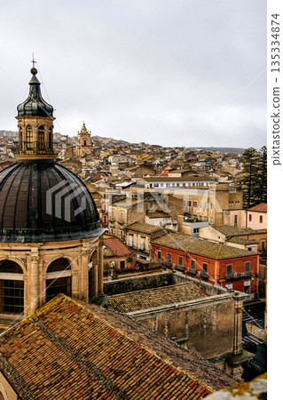 Panoramic View Over Ragusa From Cathedral Of San Giovanni Battista: Historic Sicilian City Rooftops, Church Domes, And Dense Stone Architecture Under Overcast Sky 135334874