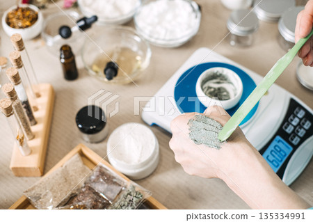 Hand of person applying cosmetic product to skin with spatula for sensory feedback. Texture analysis, product trial, cosmetic evaluation. Hand of person applying cosmetic product to skin with spatula for sensory feedback. Texture analysis, product trial, cosmetic evaluation. 135334991
