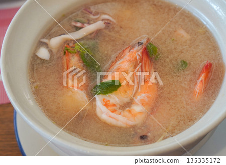 top view Seafood tom yum with clear soup in a ceramic cup on a galvanized plate on table background, food, eat, object, copy space top view Seafood tom yum with clear soup in a ceramic cup on a galvanized plate on table background, food, eat, object, copy space 135335172