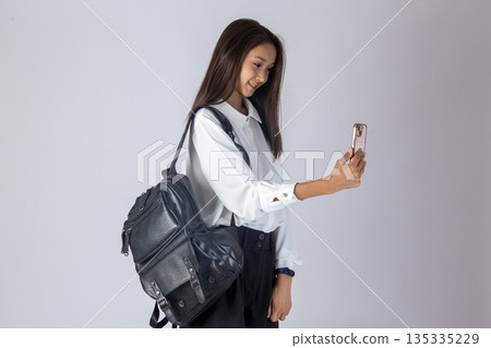 Young woman taking selfie with smartphone and smiling happily in studio Young woman taking selfie with smartphone and smiling happily in studio 135335229