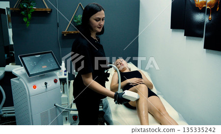 Beautician performing laser treatment on legs Beautician performing laser treatment on legs 135335242