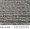 Close view of dry cultivated soil with parallel ridges creating natural agricultural texture and repetitive pattern 135335291