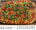 Homemade rectangular pizza topped with fresh arugula and cherry tomatoes. Golden baked crust with melted cheese creates an appetizing look 135335293