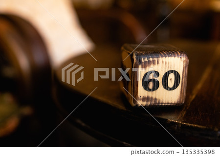 The number 60 on the wooden cube is burned with large symbols 135335398