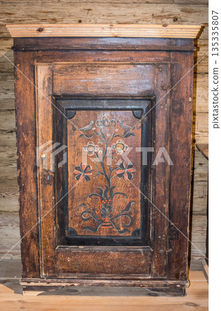 A vintage wooden cabinet features detailed carvings and a unique pattern 135335807