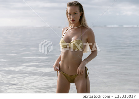 Beautiful young woman in bikini relaxing at beach. Sexy model staying in ocean Beautiful young woman in bikini relaxing at beach. Sexy model staying in ocean 135336037