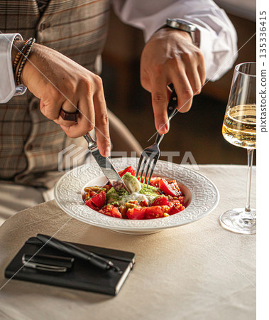 Person eating burrata cheese salad with tomatoes Person eating burrata cheese salad with tomatoes 135336415