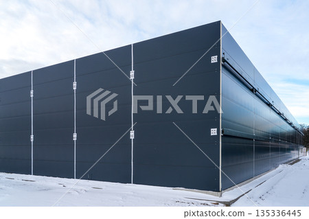 Modern industrial building with dark sandwich panel facade at snowy construction site Modern industrial building with dark sandwich panel facade at snowy construction site 135336445