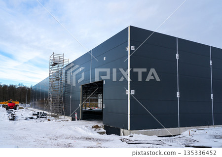 Modern industrial building with sandwich panel facade under construction in winter 135336452