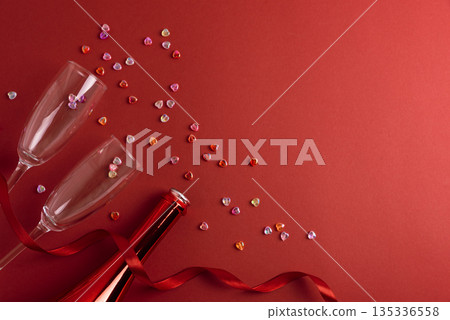 Champagne Bottle and Flute Glasses with Colorful Hearts on Red Background. Valentines Day Celebration Champagne Bottle and Flute Glasses with Colorful Hearts on Red Background. Valentines Day Celebration 135336558