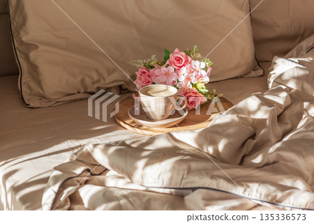 Cappuccino Cup and Flowers on Tray with Satin Bedding in Sunlight. Valentine's or Mother's Day Celebration Cappuccino Cup and Flowers on Tray with Satin Bedding in Sunlight. Valentine's or Mother's Day Celebration 135336573
