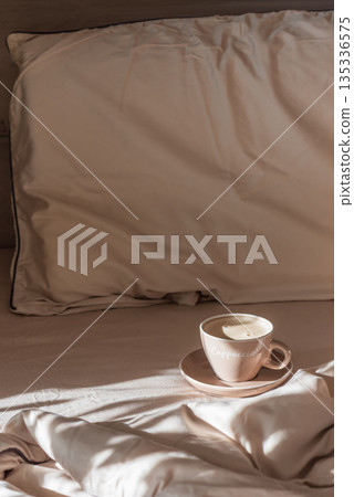 Cappuccino Cup on Cozy Bed with Sunlight and Beige Bedding Cappuccino Cup on Cozy Bed with Sunlight and Beige Bedding 135336575
