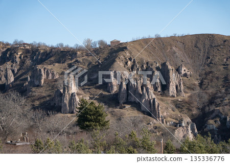 Rocky hills with caves and rugged cliffs in Khndzoresk, Armenia, under a clear blue sky, earthy tones and quiet natural atmosphere 135336776