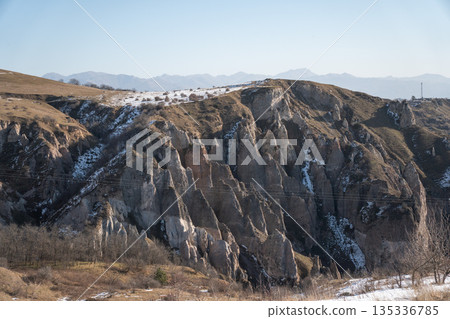 Rocky canyon landscape in Armenia with steep cliffs, layered stone formations, patches of snow, soft winter sunlight creating calm, natural atmosphere 135336785