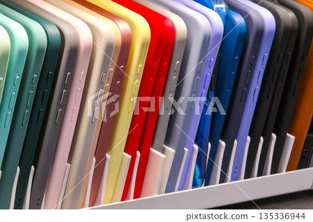 Colorful smartphone cases neatly arranged in vertical row on retail display shelf 135336944
