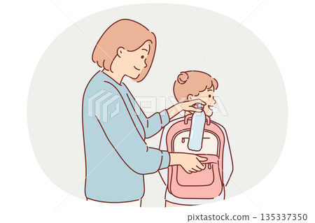 Mom puts bottle of water in daughter school backpack, taking care of child leaving for walk or study Mom puts bottle of water in daughter school backpack, taking care of child leaving for walk or study 135337350