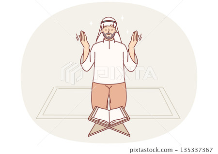 Muslim man prays on knees in front koran, observing islamic ritual during holy month of ramadan Muslim man prays on knees in front koran, observing islamic ritual during holy month of ramadan 135337367