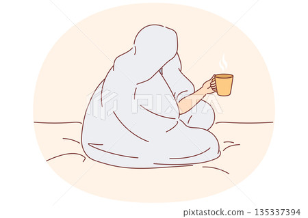 Man drinks coffee sitting on bed and wrapped in blanket to warm up after walk along winter street 135337394