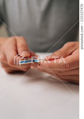 Vertical cropped shot electrician hands splitting modern data cable using cutter knife, revealing inner wires, essential for network setup, internet connection, professional electrical work. 135337470