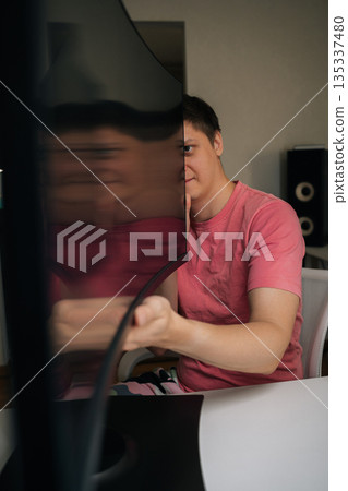 Vertical portrait of young man holding and inspecting ultrawide monitor with glossy screen reflecting red shirt, checking hardware and displaying curved display for testing new technology. Vertical portrait of young man holding and inspecting ultrawide monitor with glossy screen reflecting red shirt, checking hardware and displaying curved display for testing new technology. 135337480
