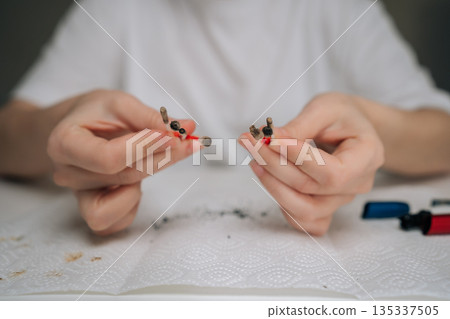 Closeup of person hands performing maintenance service on heated tobacco device, cleaning electronic cigarette with cotton swab and keeping vape device in proper condition, close-up cropped shot. 135337505
