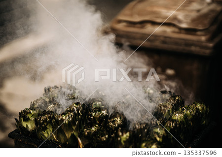 Fresh Artichokes Barbecue At Catania Market In Sicily: Trimming And Steaming Green Vegetables On Hot Surface In Traditional Street Food Scene 135337596