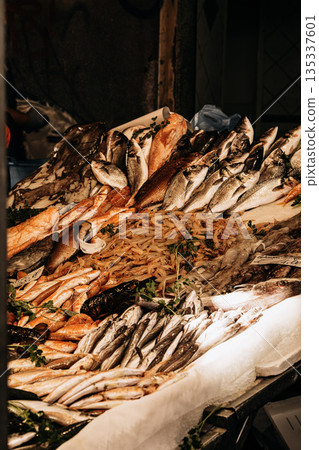 Fresh Seafood Display At Market Stall: Raw Fish, Squid, And Shellfish Arranged In White Crates On Ice In Indoor Food Market Setting 135337601