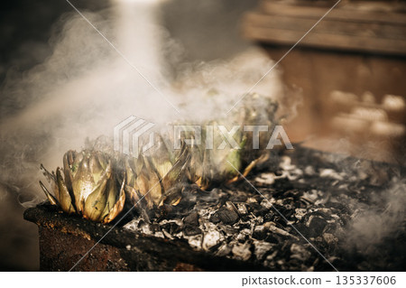 Fresh Artichokes Barbecue At Catania Market In Sicily: Trimming And Steaming Green Vegetables On Hot Surface In Traditional Street Food Scene 135337606