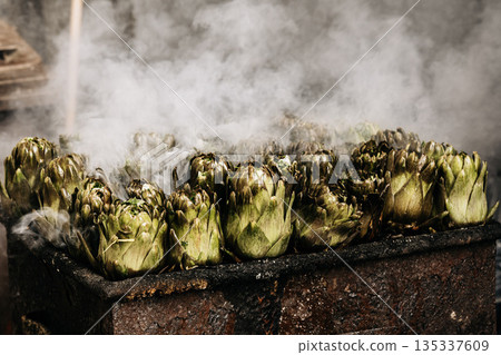 Fresh Artichokes Barbecue At Catania Market In Sicily: Trimming And Steaming Green Vegetables On Hot Surface In Traditional Street Food Scene 135337609