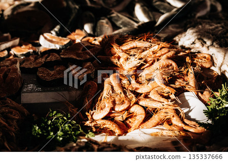 Fresh Seafood Display At Market Stall: Raw Fish, Squid, And Shellfish Arranged In White Crates On Ice In Indoor Food Market Setting Fresh Seafood Display At Market Stall: Raw Fish, Squid, And Shellfish Arranged In White Crates On Ice In Indoor Food Market Setting 135337666
