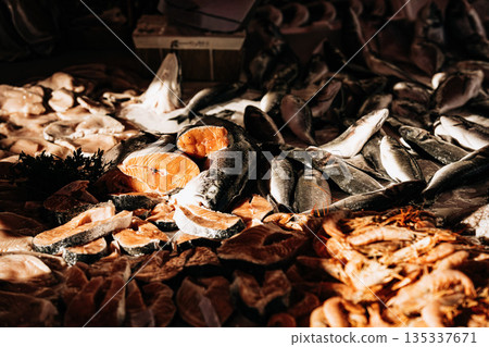 Fresh Seafood Display At Market Stall: Raw Fish, Squid, And Shellfish Arranged In White Crates On Ice In Indoor Food Market Setting 135337671