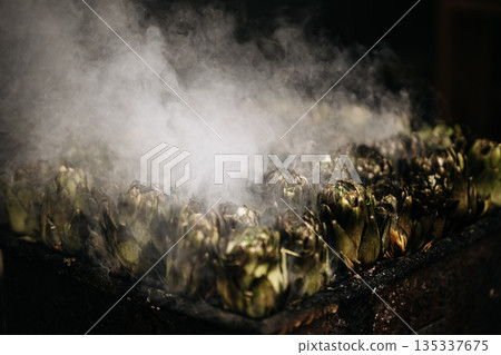 Fresh Artichokes Barbecue At Catania Market In Sicily: Trimming And Steaming Green Vegetables On Hot Surface In Traditional Street Food Scene 135337675