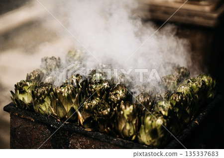Fresh Artichokes Barbecue At Catania Market In Sicily: Trimming And Steaming Green Vegetables On Hot Surface In Traditional Street Food Scene 135337683