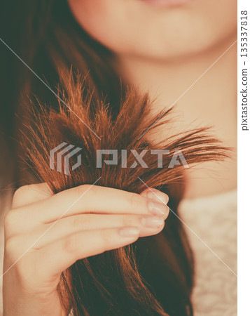 Woman looking at her dry hair ends Woman looking at her dry hair ends 135337818